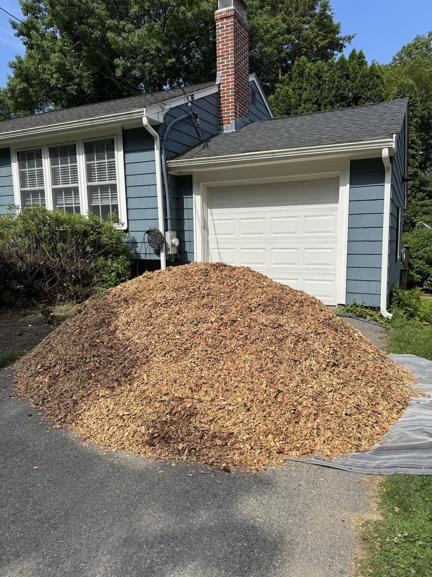 Six cubic yard pile of Playground Mulch delivered to a residential driveway in Arlington, Massachusetts for a landscaper partner installing for a client