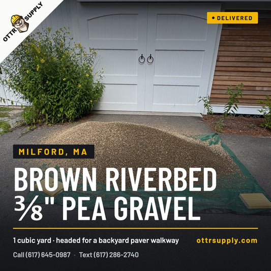 One cubic yard of Brown Riverbed ⅜" pea stone delivered on a tarp in a Milford, MA driveway for a backyard paver walkway