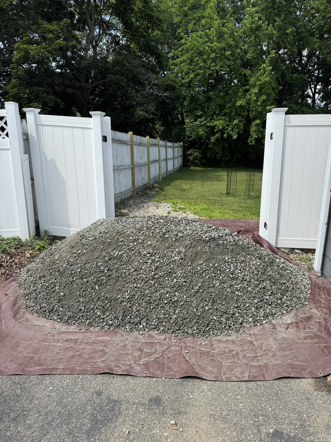 Three cubic yard pile of Dense Pack gravel delivered to a residential driveway in Malden, Massachusetts for a backyard DIY shed foundation