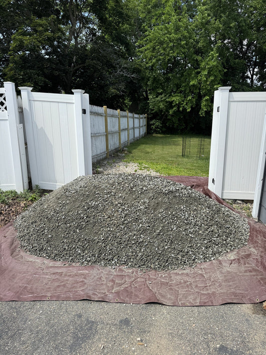 Three cubic yard pile of Dense Pack gravel delivered to a residential driveway in Malden, Massachusetts for a backyard DIY shed foundation