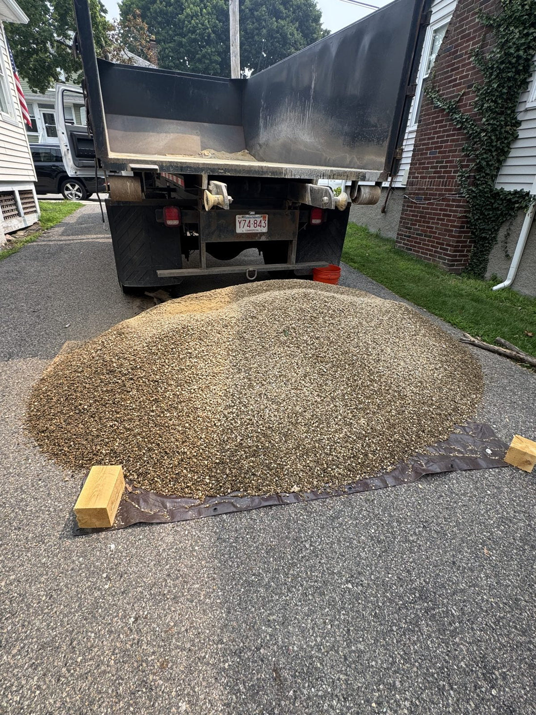 Ottr dump truck unloading bulk stone in a Massachusetts driveway