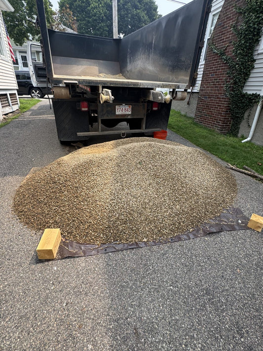 Ottr dump truck unloading bulk stone in a Massachusetts driveway