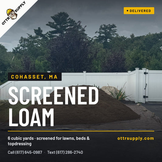6 cubic yards of screened loam delivered by dump truck to a driveway in Cohasset, MA by Ottr Landscape Supply, for backfilling a block retaining wall and rebuilding an eroded hillside lawn