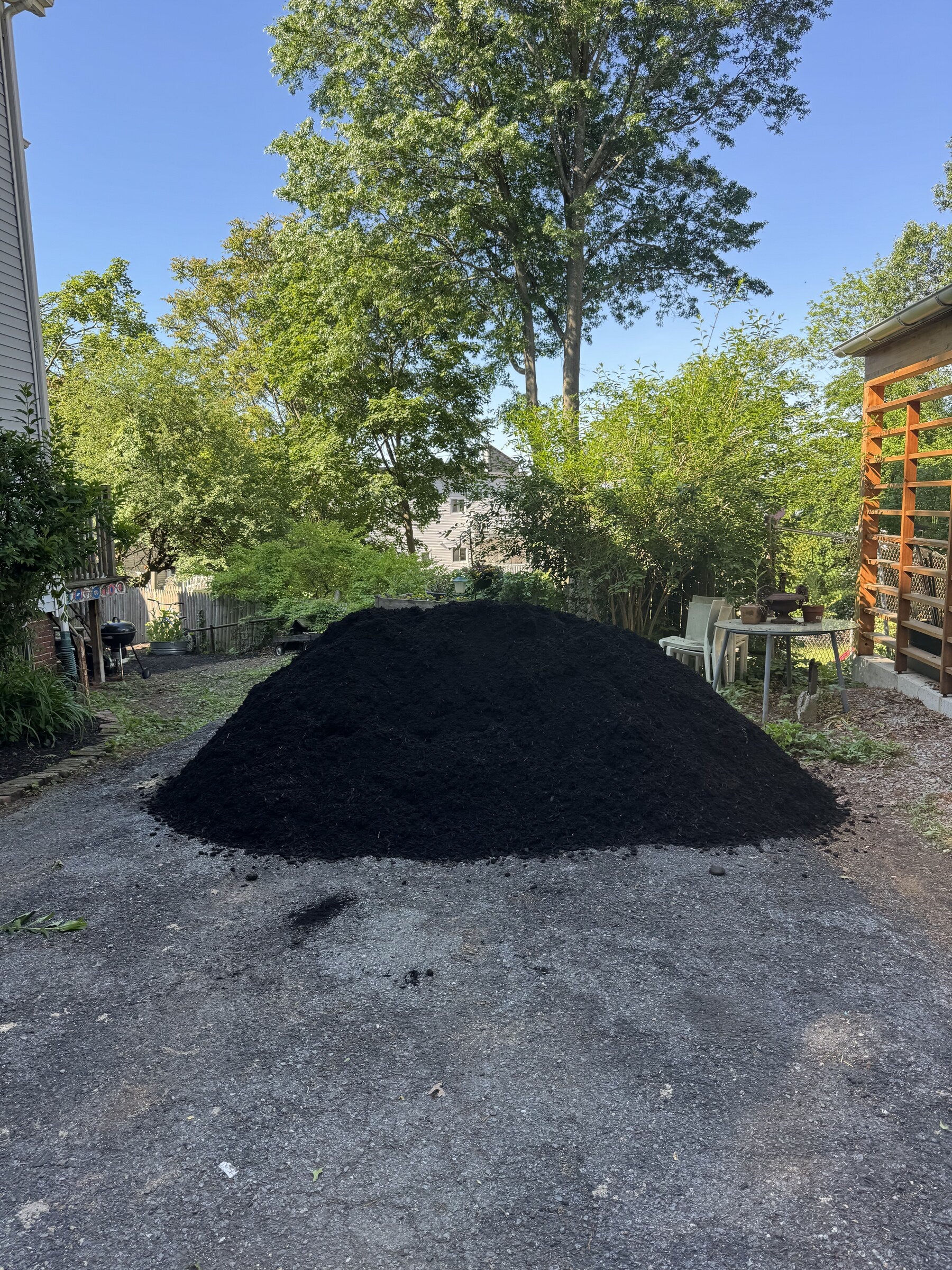 Pile of fresh black mulch delivered to a residential backyard in Roxbury, Massachusetts